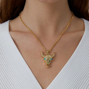 Golden western bull head skull pendant necklace with turquoise eyes worn by a model