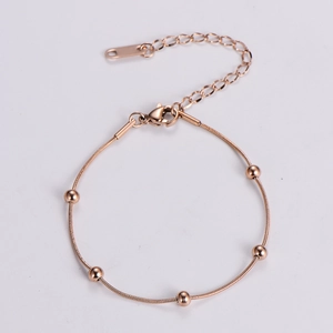Detail of rose gold beaded bracelet featuring polished spheres and adjustable chain