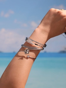 Macro shot of silver-tone stackable bracelets featuring snake and floral motifs