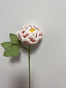 Detailed view of handmade pink gradient crochet peony with green leaves and stem
