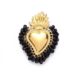 Detailed close-up of a vintage golden heart pendant with decorative black beads on the edges