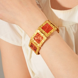 Macro shot of vintage gold square bracelet with red enamel inlay on a female wrist
