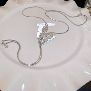 Detailed view of silver butterfly pendant with snake chain on white ceramic tray