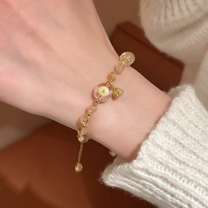 Detail of adjustable beaded bracelet with yellow citrine crystals and golden coin charm