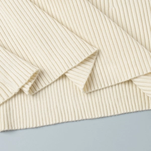 Close-up of cream white ribbed knit fabric showing vertical texture and stitching detail