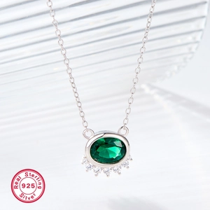 Macro shot of 925 sterling silver necklace with oval green gemstone and diamond detail