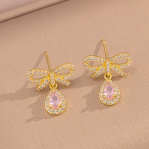 Detail of gold bow earrings featuring teardrop pink stones and sparkling zircon accents