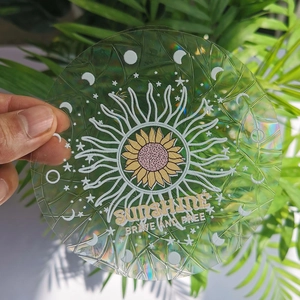Rainbow suncatcher window sticker with sunflower and sunshine design held near green leaves