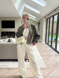 Olive green cropped zip jacket with white tank top and cream-colored wide leg trousers