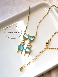 Détail d'un collier doré avec pendentif cœur bleu en zircon et chaîne réglable de 45+5 cm