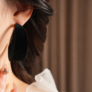 Close-up of black velvet C-shaped earrings worn by a model for a stylish aesthetic