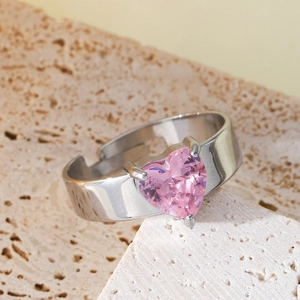 Polished silver stainless steel ring with pink heart crystal on beige travertine stone