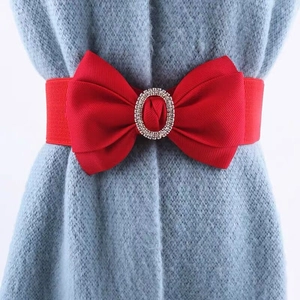 Roter elastischer Taillengürtel mit Schleife und Strass-Schnalle auf blauem Pullover
