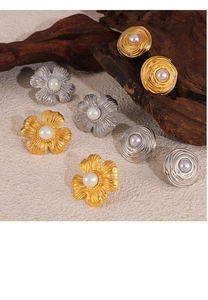 Detailed macro view of vintage gold and silver floral earrings with pearl on aged wood