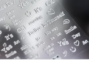 Macro detail of 3D embossed silver nail stickers with heart and smiling face patterns