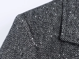 Detailed close-up of high-quality black and white herringbone tweed fabric with fine stitching