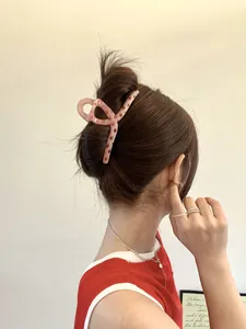 Macro view of a 13cm pink and red polka dot hair claw clip used in a messy bun hairstyle
