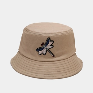 Close-up of colorful dragonfly embroidery on beige cotton bucket hat with stitched brim