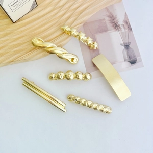 Detailed view of six gold geometric hair clips with star and textured metallic finishes