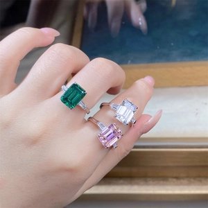 Detailed view of three emerald-cut zircon rings in green, white, and pink on model's hand