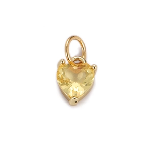 Macro shot of gold-plated heart pendant with yellow zircon and evil eye drip oil detail