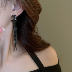 Close-up of model wearing black rhinestone tassel earrings with multi-layered drop design