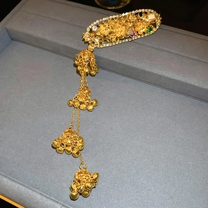 Detail of a vintage Chinese gold hairpiece with floral patterns and colorful gemstones