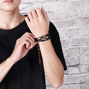 Dettaglio del bracciale multistrato in pelle nera con simbolo dell'infinito sul polso