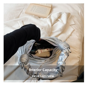 Detail view of the silver pleated handbag interior showing capacity for makeup and phone