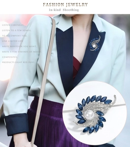 Detailed view of silver swirl brooch with navy marquise crystals and a center white pearl
