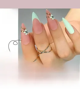 Macro detail of long stiletto press-on nails with mint green French tips and floral gems