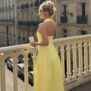 Dettaglio di un abito giallo accollato con schiena scoperta e gonna a pieghe