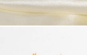 Detail of 18K gold-plated spherical earrings on cream satin fabric and white background