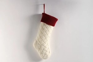Close-up of cream knit Christmas stocking with red ribbed cuff and textured weave patterns