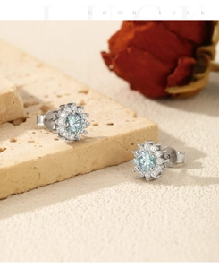 Detailed view of silver snowflake earrings with green moissanite on a beige stone base