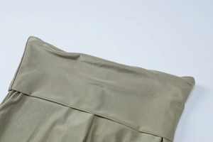 Detailed macro shot of the waist tailoring and fold-over craftsmanship on olive trousers