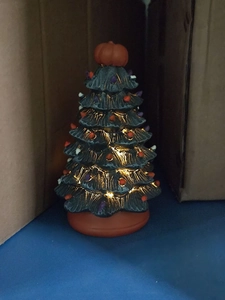 Detail of a lighted Halloween tree with a pumpkin top and colorful glowing ornaments