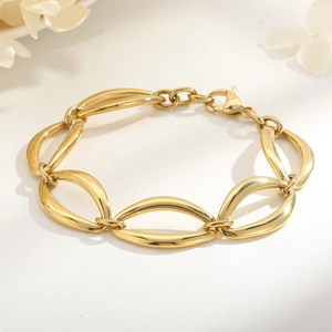 Detailed close-up of polished gold-plated hollow oval links and lobster clasp on bracelet