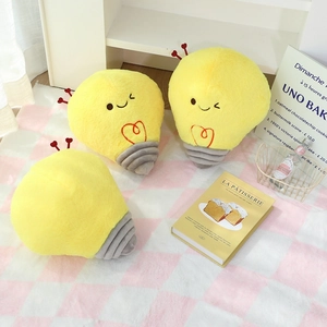 Set of three cute cartoon light bulb plush pillows with heart antennas on checkered blanket
