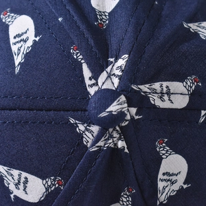 Close-up of navy canvas baseball cap showing white pigeon pattern and fine stitching detail