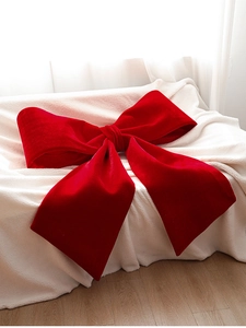 Detailed texture of a large red velvet Christmas bow on a soft white fleece blanket
