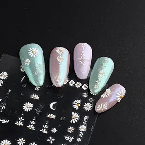 Macro shot of 5D embossed white daisy nail art stickers and finished floral manicures