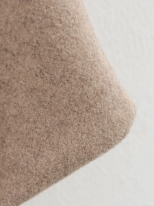 Gros plan sur la texture laineuse beige clair montrant les fibres douces et les coutures