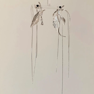 Detail view of silver leaf tassel earrings with black beads on a display stand