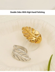 Detailed view of high polished gold and silver leaf rings on a white textured stand