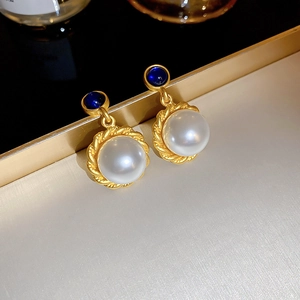Detail of vintage gold pearl earrings with blue gemstone accents and braided texture