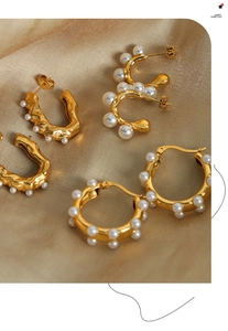 Detailed close-up of three pairs of gold-plated titanium earrings with glossy pearls