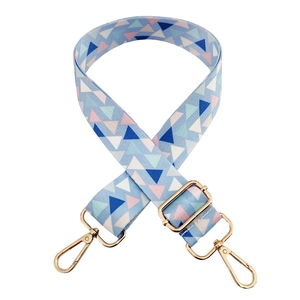 Detail of adjustable wide bag strap with blue geometric triangles and gold metal hooks