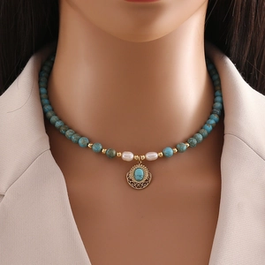 Handmade necklace with natural turquoise beads, pearls and gold pendant on female model