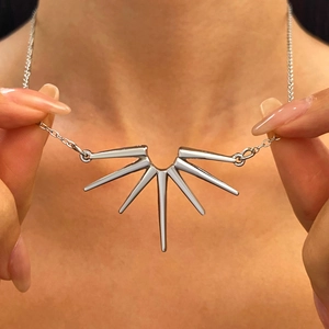 Gros plan d'un collier pendentif tournesol argenté avec un design rayonnant porté par un modèle